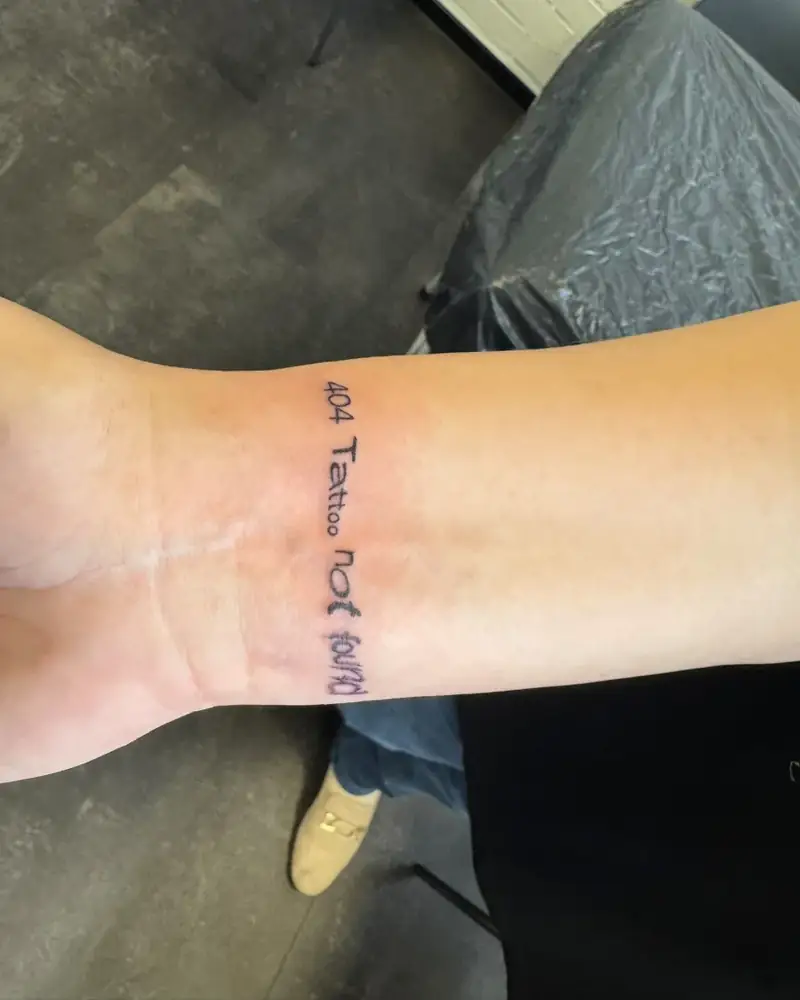 Frisch gestochenes Tattoo: Schriftzug 404 Tattoo not found am Handgelenk