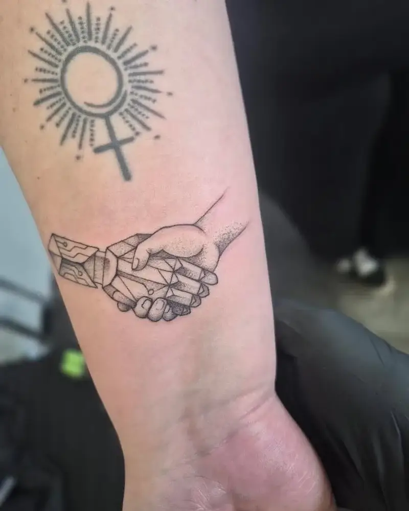 Frisch gestochenes Tattoo: Handschlag zwischen Menschenhand und Roboterhand