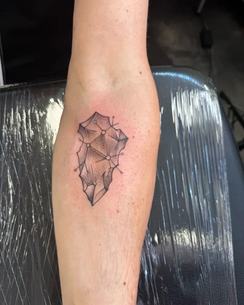 Frisch gestochenes Tattoo: Feuersteinspitze mit Schaltkreis-Knoten auf dem Unterarm